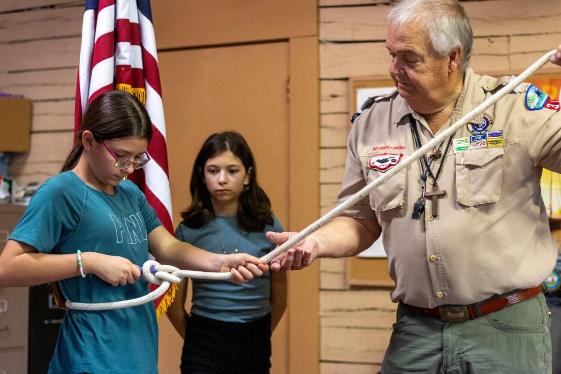 代理团长George Bergfeld Sr.与Alice Schmidt练习救生绳结，Miamor Martinez在旁观看学习